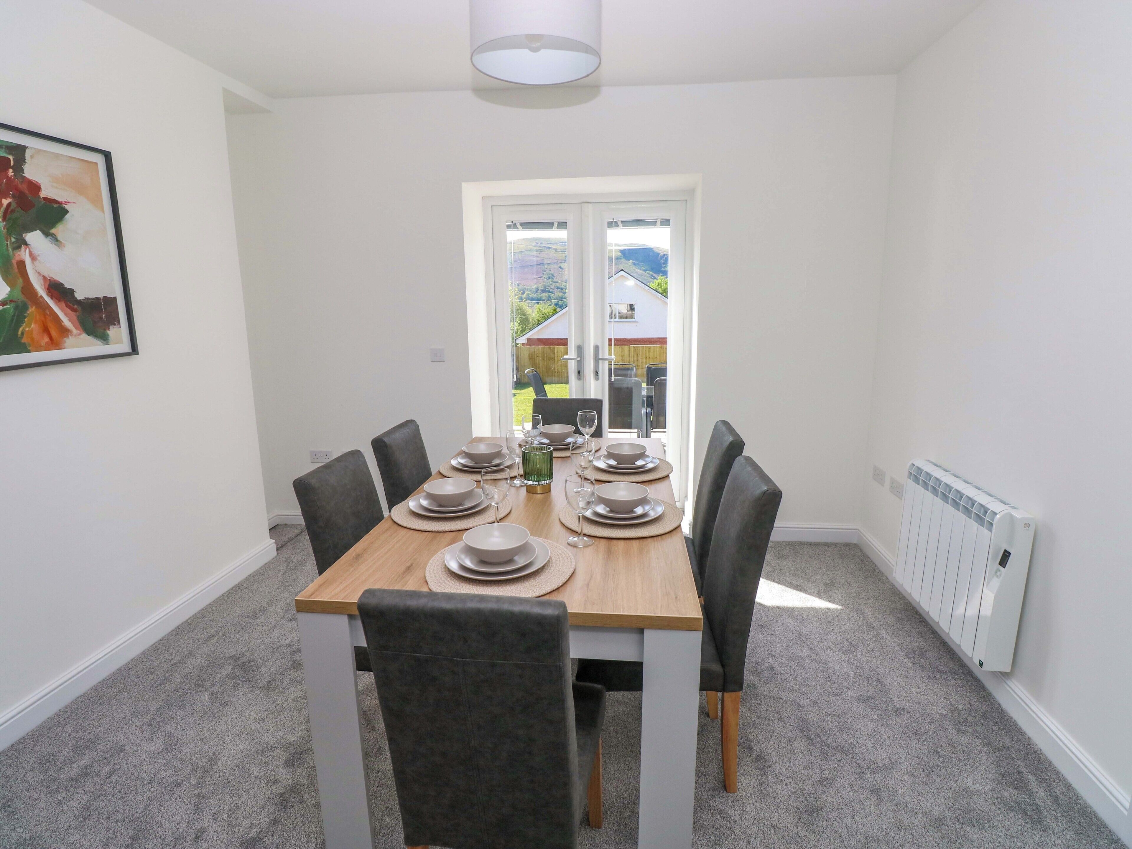 A dining room with a table set for four, chairs, a radiator, and a door leading outside.