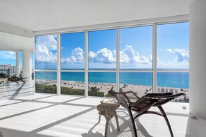 Ein geräumiger Balkon mit großen Fenstern und Blick auf einen Strand.