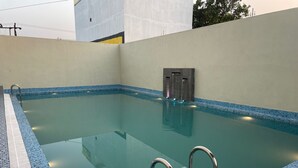 A swimming pool with clear water, metal handrails, and a tiled edge. - LIMELIGHT Hotel & Restaurant (Rishikesh)