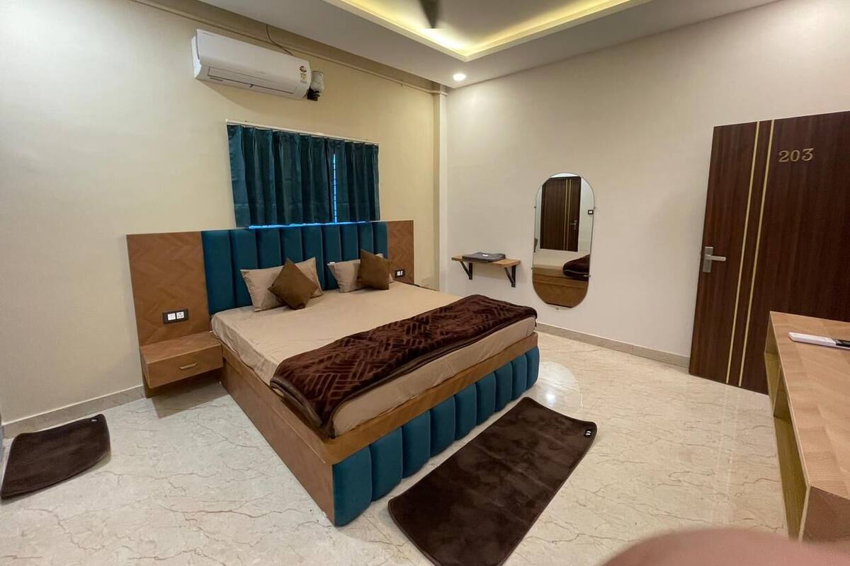 A modern bedroom with a bed, bedside tables, a mirror, a wardrobe, and an air conditioning unit.