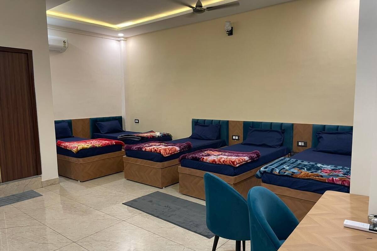 A hotel room with four beds, a desk, and a chair.