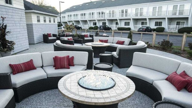 A courtyard with outdoor seating, a central fire pit, and a building with balconies in the background. - The Best Unit at the Best Resort during the Best Week on Cape Code (Yarmouth)