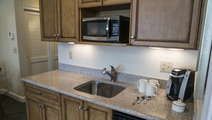 A kitchen with wooden cabinets, a stainless steel sink, a microwave, a coffee maker, and a dishwasher. - The Best Unit at the Best Resort during the Best Week on Cape Code (Yarmouth)