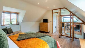 Un dormitorio con cama, cómoda, ventana con persianas y una escalera que conduce a un nivel superior.