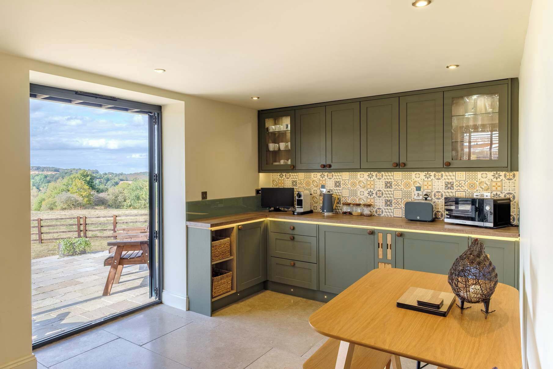 A modern kitchen with a large window, a dining table, and a view of the outdoors.