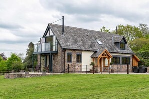 A two-story stone house with a balcony, a wooden porch, and a fenced yard. - Longdale Barn (Newtown Linford)