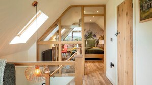 Una habitación estilo loft con techo inclinado, una escalera y una cama.