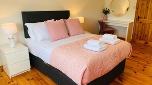 A neatly made bed with pillows, a bedside lamp, and a folded towel on a wooden floor. - The Mis Kerry Escape (Castlemaine)