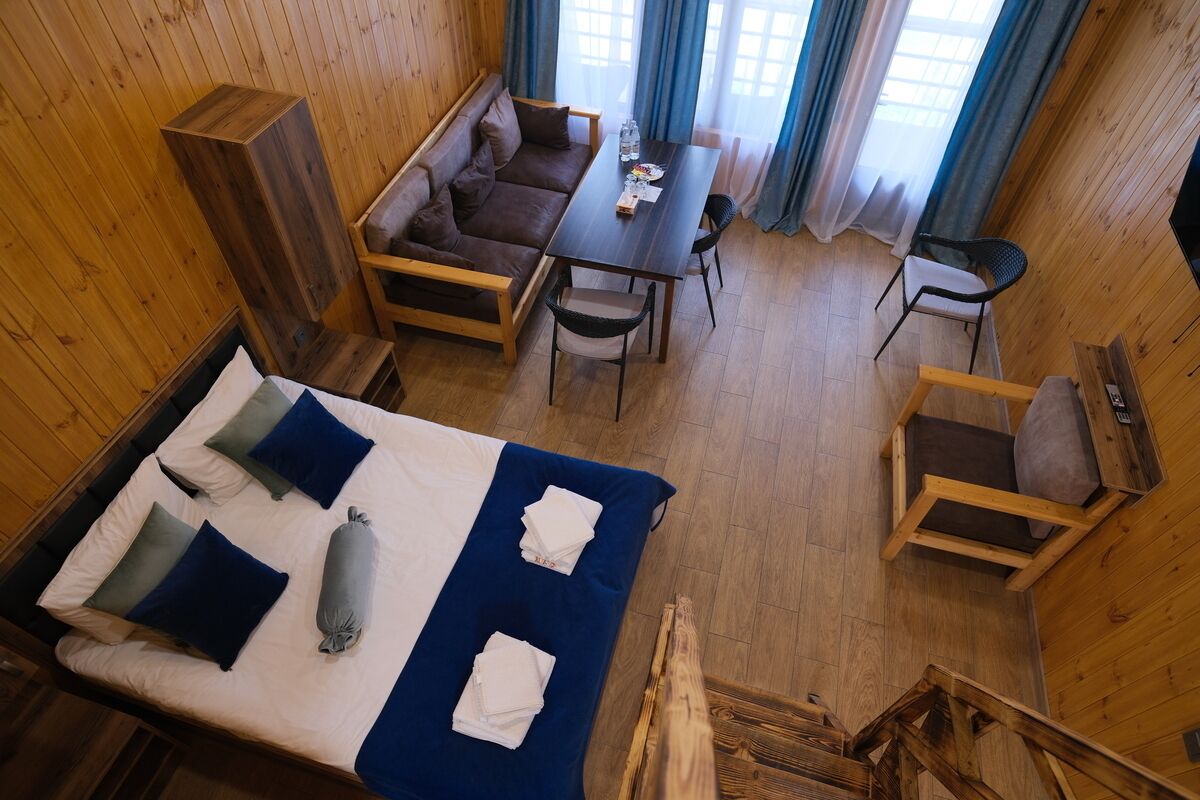 A room with a bed, a sofa, a dining table, and a chair.