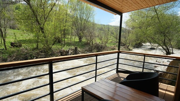 Una terraza de madera con vista a un río, rodeada de árboles.