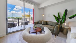 A modern living room with a sofa, a round coffee table, and a large plant. - Studio in Midtown | Standard Miami - Pool & Gym (Miami)