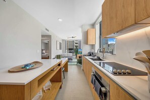 Eine moderne Küche mit Holzausstattung, einer zentralen Kochinsel und Blick in den Wohnbereich.