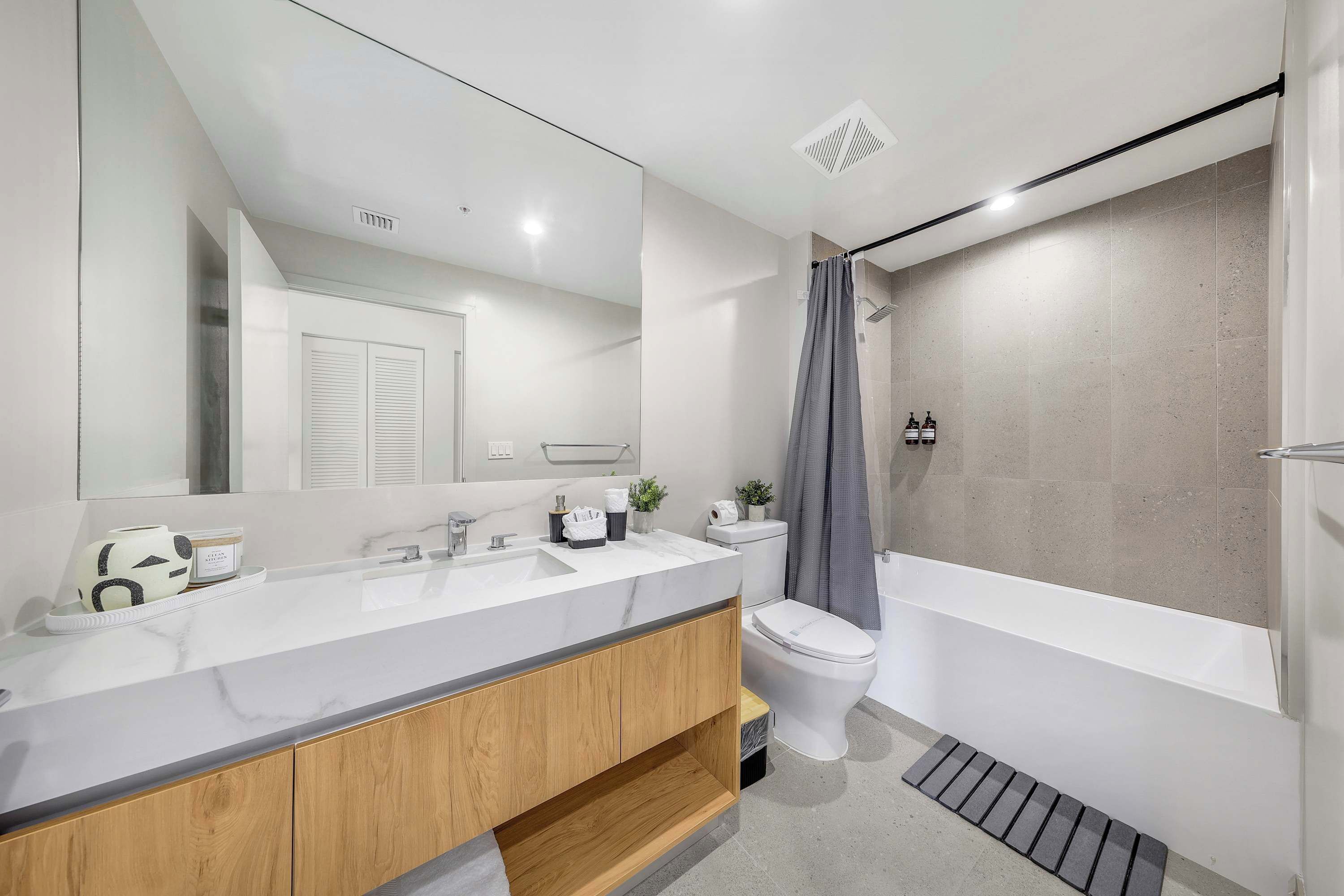 A modern bathroom with a vanity, toilet, and bathtub.