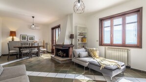 Una sala de estar con chimenea, sofá, mesa de comedor y sillas.