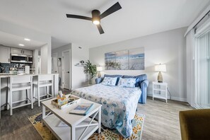 Ein modernes Schlafzimmer mit Bett, Nachttischen, einem Schreibtisch und einem Deckenventilator.