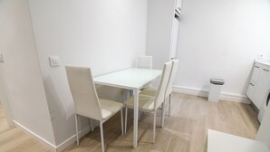 Une pièce avec une table blanche, quatre chaises, un meuble blanc et un plancher en bois de couleur claire.