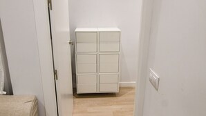 Un couloir étroit avec une armoire blanche et un canapé beige.