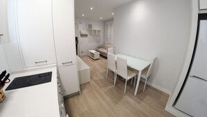 Une cuisine moderne avec des meubles blancs, une table à manger avec des chaises et un four encastré.
