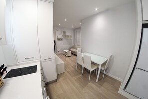 Een moderne keuken met witte kasten, een eettafel met stoelen en een inbouwoven.