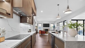 A modern kitchen with marble countertops, wooden cabinets, and pendant lighting.