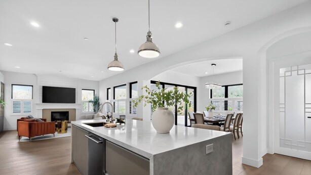 A modern kitchen with a central island, pendant lighting, and a dining area with a view.