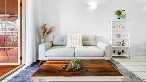 A living room with a sofa, coffee table, and a white bookshelf. - Bright Cozy Apartment Central - Modern (Darwin)
