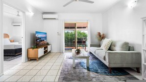 A modern living room with a sofa, TV, and a coffee table. - Bright Cozy Apartment Central - Modern (Darwin)