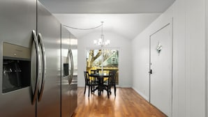 Eine Küche mit Edelstahlkühlschrank, Holzboden und einem Essbereich mit Tisch und Stühlen.