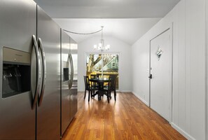 Eine Küche mit Edelstahlkühlschrank, Holzboden und einem Essbereich mit Tisch und Stühlen.