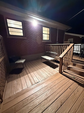 A wooden deck with a railing, a bench, and a window.