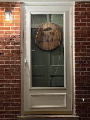 A door with a glass panel and a wooden sign that reads 'My Old Kentucky Home.'