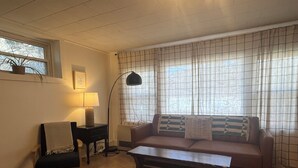 A living room with a sofa, a table, a lamp, and a window with curtains.