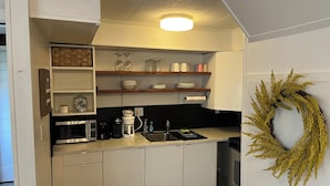 A compact kitchen with white cabinets, a microwave, a coffee maker, and a sink.