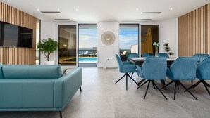 A modern interior with a sofa, dining table, chairs, and a TV. - Villa Solina Zadarvillas (Jasenice)