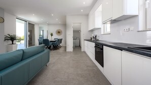 A modern kitchen with white cabinets, a black countertop, and a dining area with a teal sofa and chairs. - Villa Adriatique & Solina Zadarvillas (Jasenice)