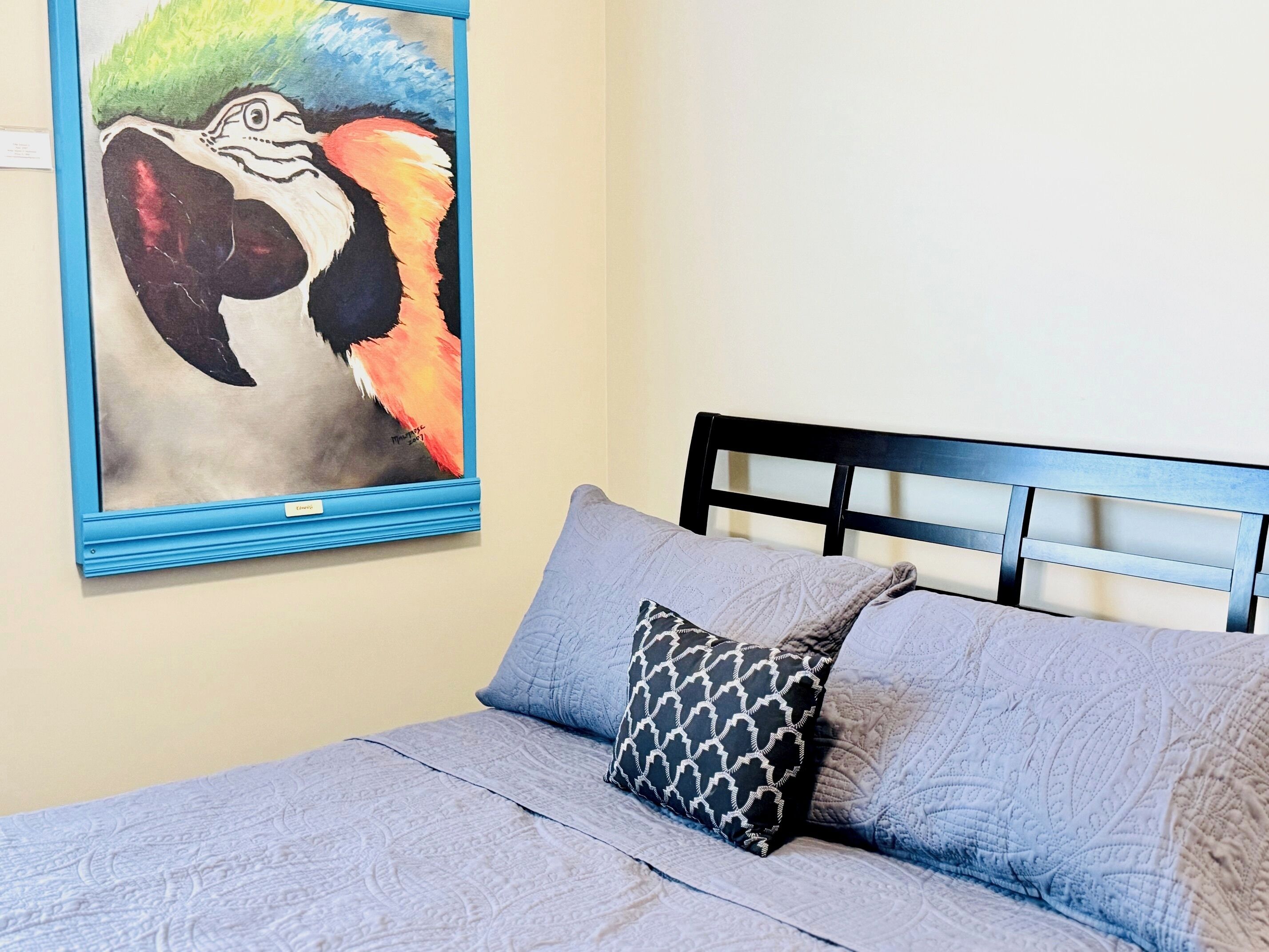 Een slaapkamer met een bed, hoofdbord, wanddecoratie en een kussen.