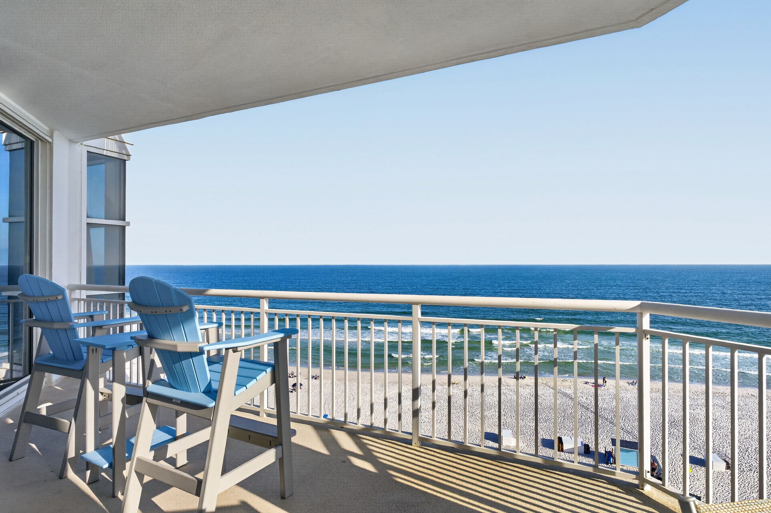 Un balcon avec vue sur l’océan, une balustrade et deux chaises.