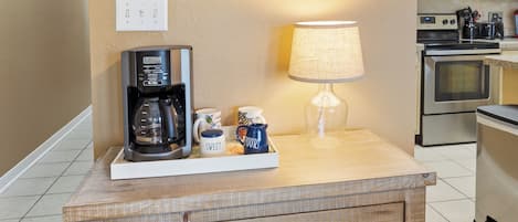 Una cocina con mostrador de madera, cafetera, lámpara y un cuadro en la pared.