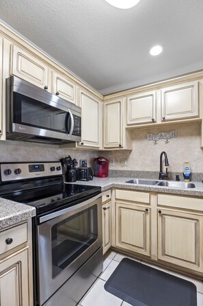 A kitchen with stainless steel appliances, a granite countertop, and light wooden cabinets. - Condo Near Beach with Pool PKRM (Pensacola)
