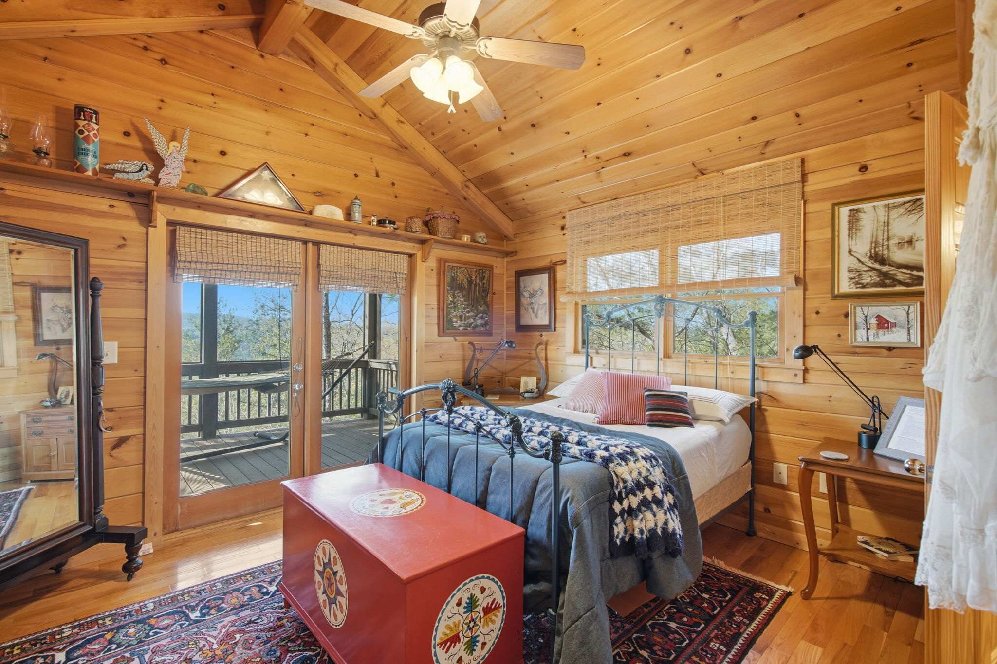 A wooden cabin with a bed, a desk, and a view of the outdoors.