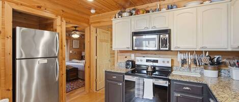 Una cocina con armarios de madera, electrodomésticos de acero inoxidable y piso de madera.