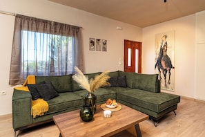 A living room with a sectional sofa, a coffee table, a vase with dried plants, and a painting on the wall. - Sea view villa Noemi (Kato Gouves)