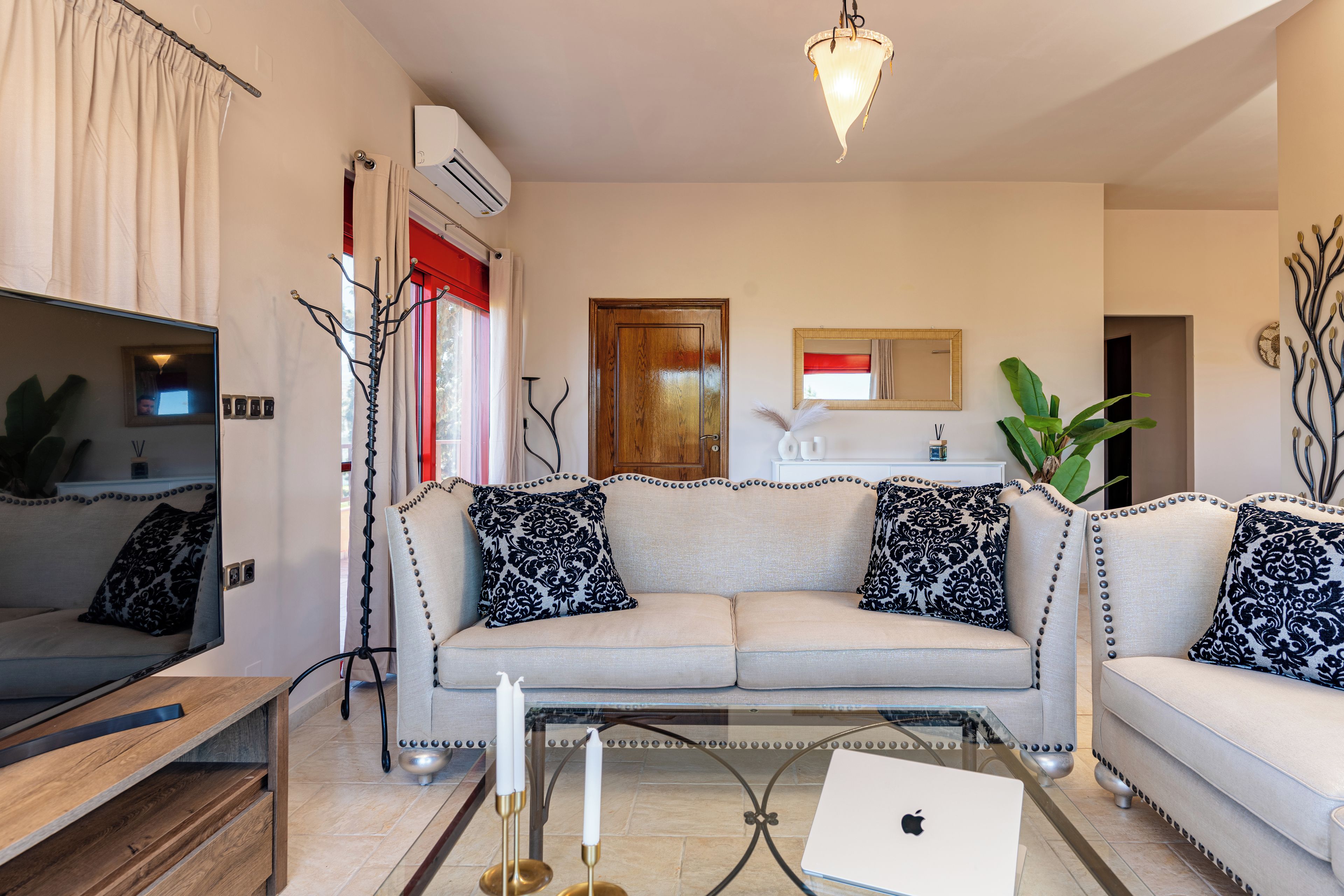 Una sala de estar con sofá, mesa de centro, televisor y ordenador portátil.