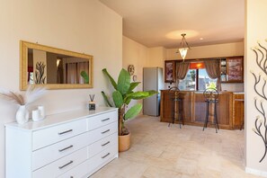 A modern kitchen with a white countertop, a large potted plant, and a bar area with stools. - Sea view villa Noemi (Kato Gouves)