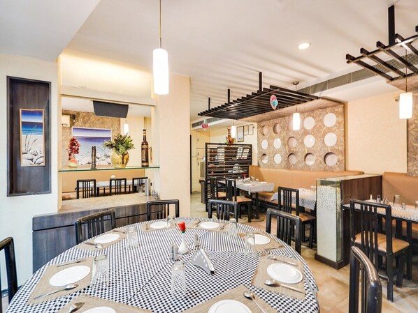 A restaurant with a round dining table set for six, a bar area, and a seating section with a patterned wall.