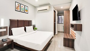 A modern bedroom with a large bed, bedside tables, a TV, and artwork on the wall. - Super Deluxe Room Palette Country Club (Surat)