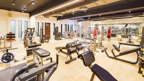 A gym with various exercise equipment, a mirror, and a wooden floor. - Super Deluxe Room Palette Country Club (Surat)