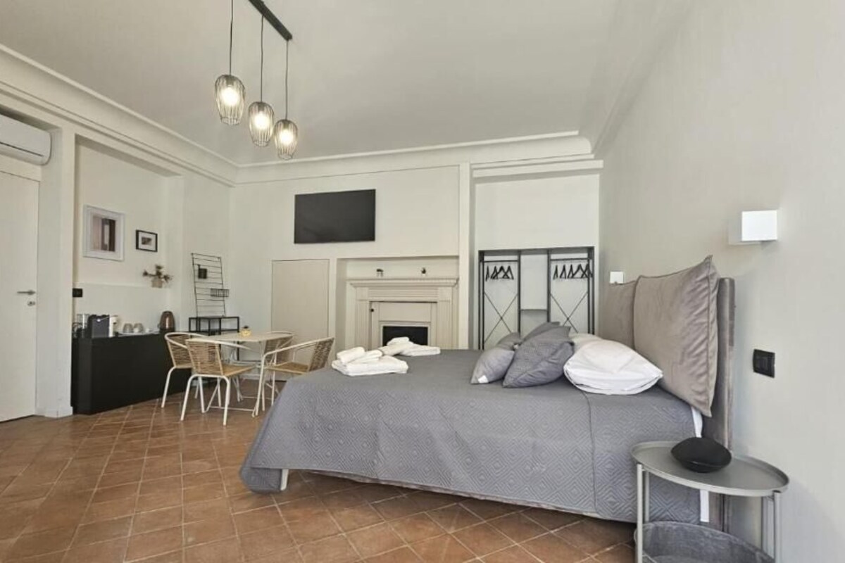 Une chambre à coucher comprenant un lit, un bureau, une chaise, une cheminée et un téléviseur.
