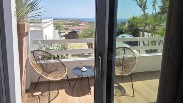 A balcony with a view of the ocean, a sliding glass door, and outdoor furniture. - Itanco Resort (Crotone)