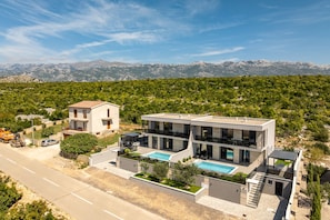 A modern two-story house with a swimming pool, a road in the foreground, and mountains in the background. - Villa Adriatique Solina Zadarvillas (Jasenice)